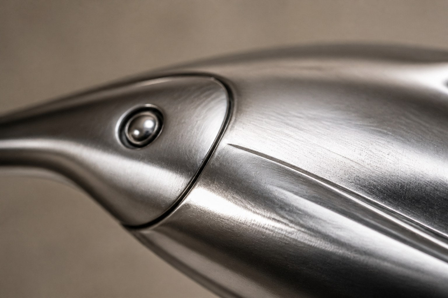 Mirror-polished stainless steel ring sculpture Estero Ø70, eight linked forms nose to tail, on a black granite block.