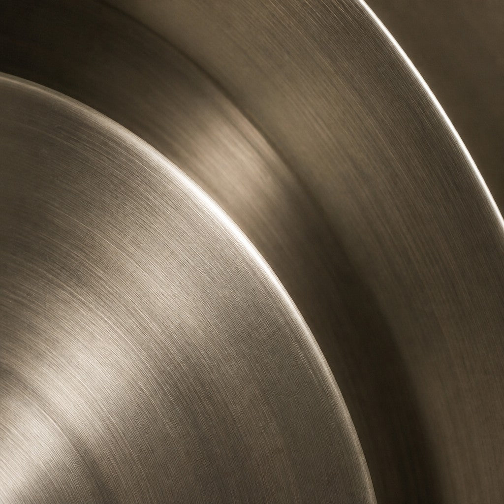 Bright silver stainless steel wall sculpture Plata, nested spun dishes stepping to a turned centre, on a plaster wall.