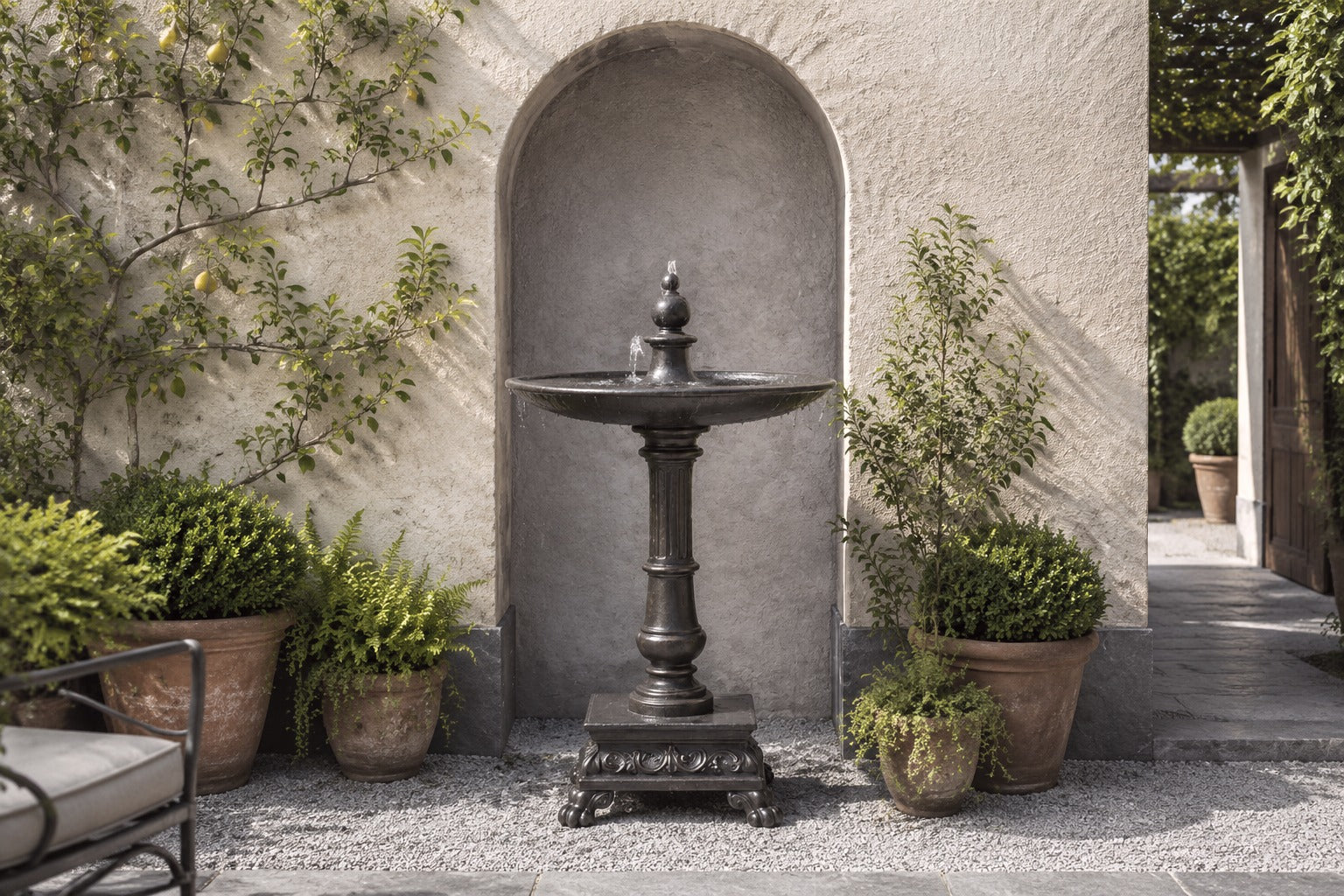 Stone pedestal fountain Mirala Ø65, dark charcoal, on a pale stone floor.