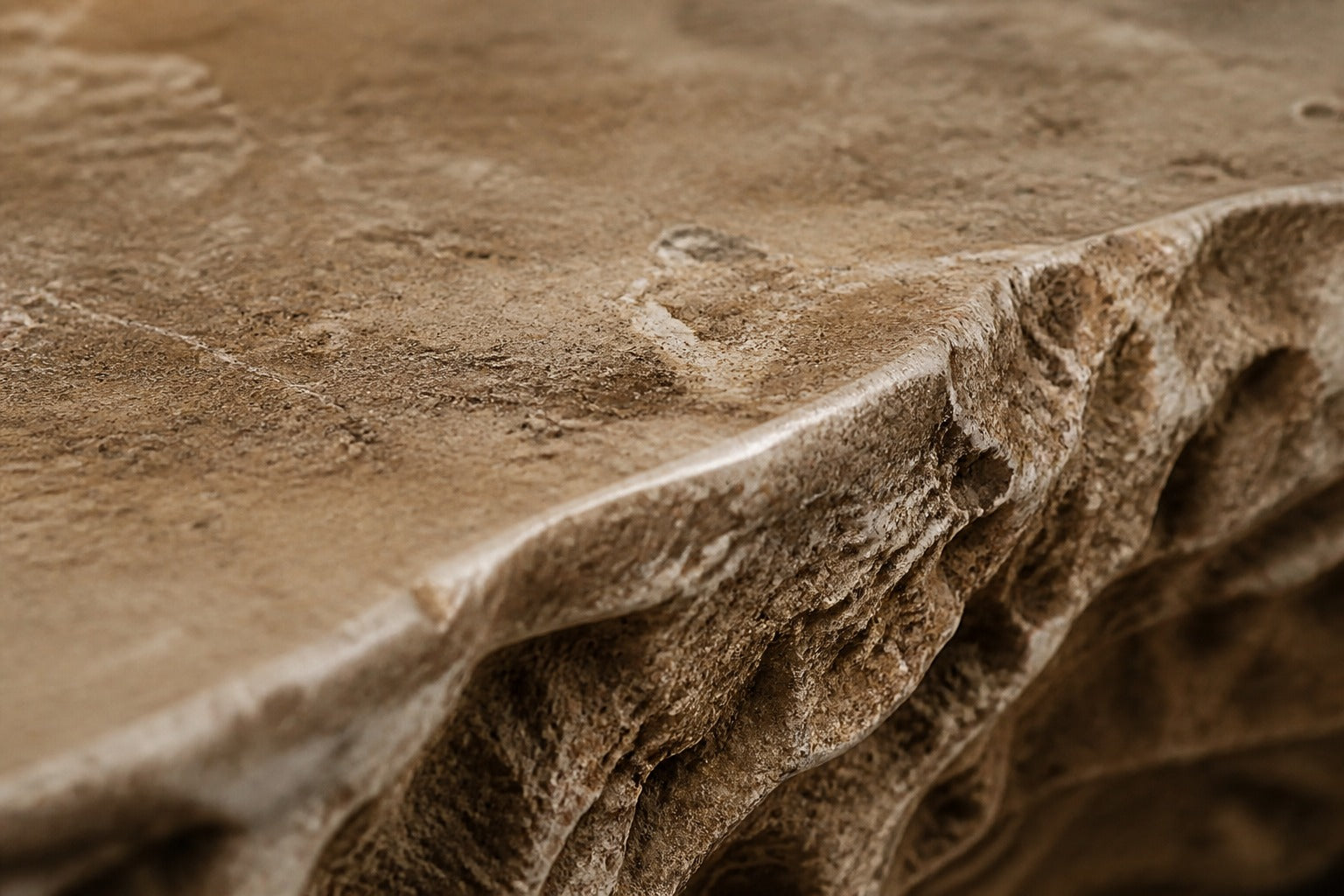 Coral travertine fire table Rimala 220, warm coral and honey, on a pale stone floor.
