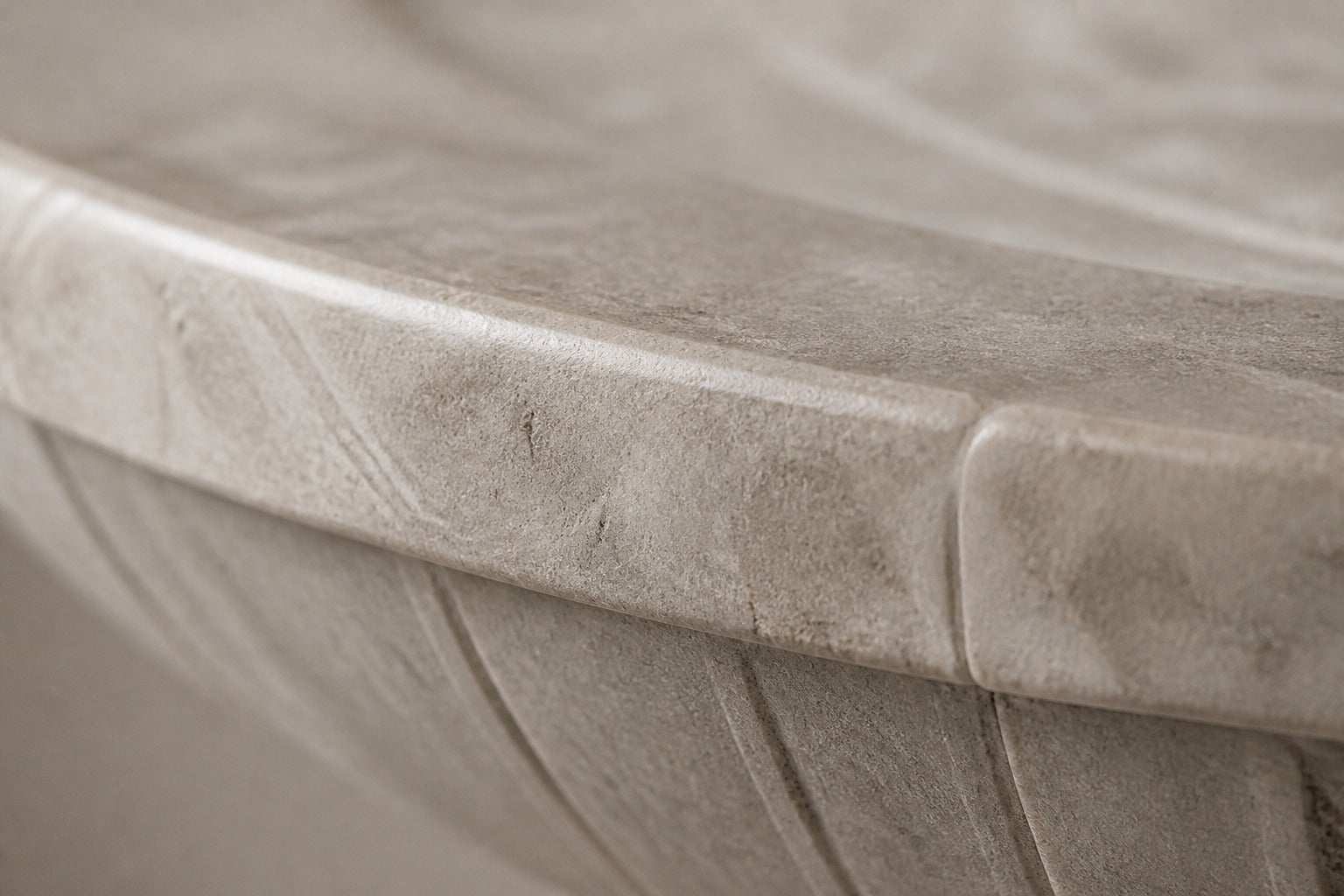 Pale limestone pedestal fountain Rivella Ø65, pale grey-white with soft veining, on a pale stone floor.