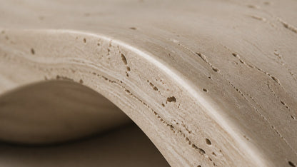 Travertine bench Hudu 180, warm cream with open pitting, on a pale stone floor.