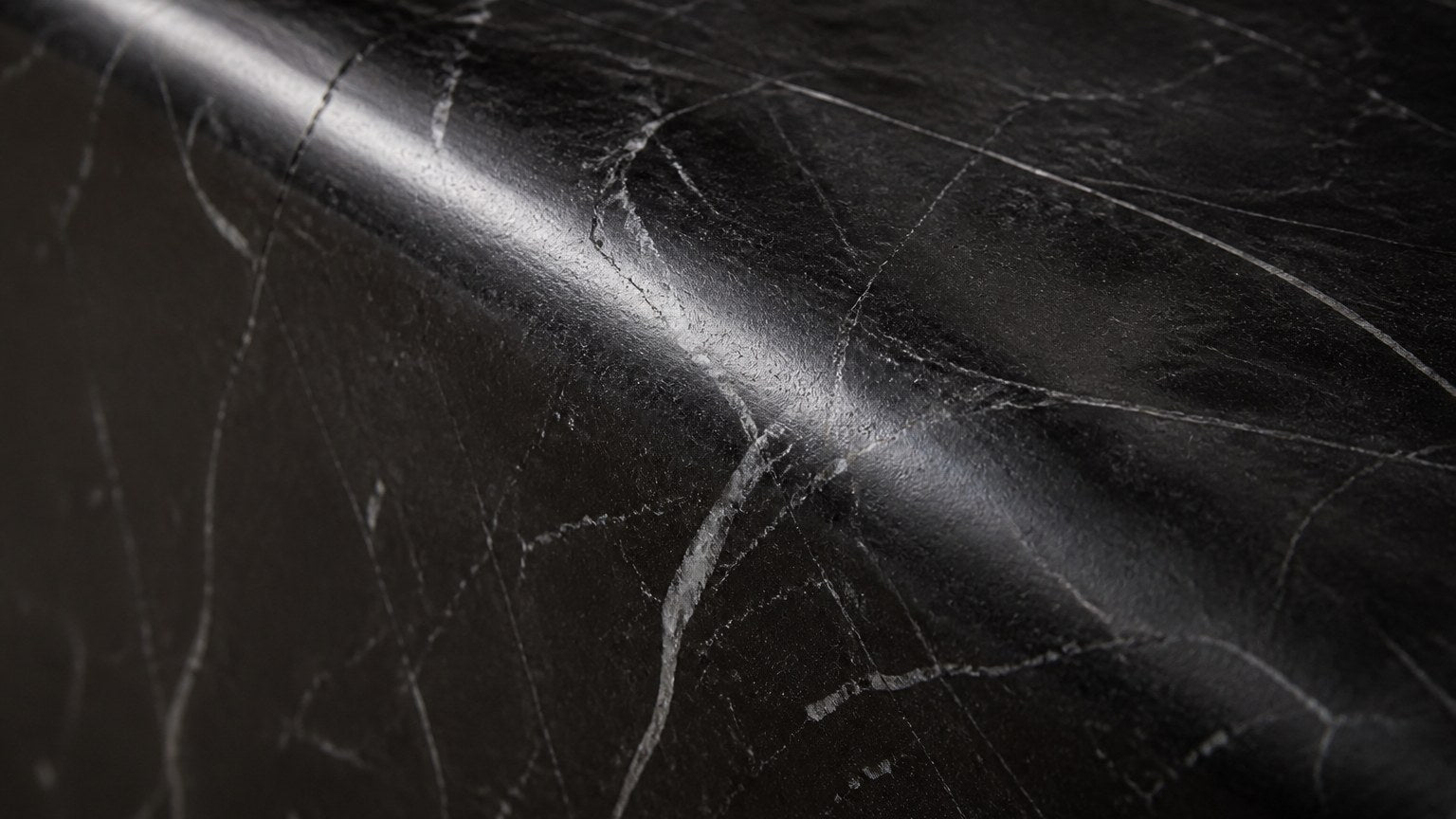 Black stone bench Yutori 180, deep black with white veining, on a pale stone floor.