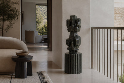 Deep green marble sculpture Almach, a column of stacked interlocking carved blocks on a fluted green marble drum plinth.