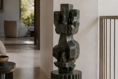 Deep green marble sculpture Almach, a column of stacked interlocking carved blocks on a fluted green marble drum plinth.