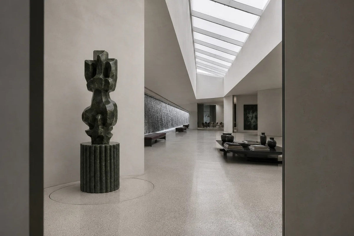 Deep green marble sculpture Almach, a column of stacked interlocking carved blocks on a fluted green marble drum plinth.
