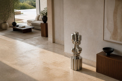Brushed stainless steel sculpture Alphard, a column of stacked interlocking blocks, on a fluted brushed steel drum plinth.