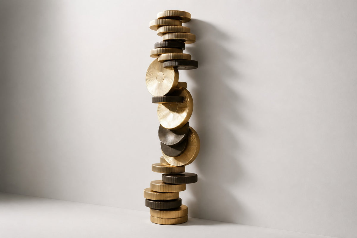 Atalaya — tower of stacked brass and bronze discs with two upright gold suns, studio side angle showing its depth
