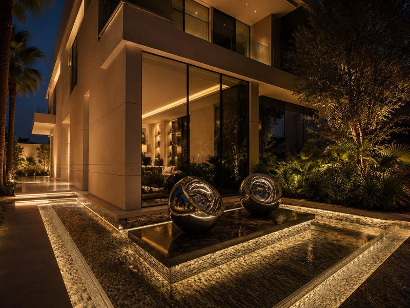 Mirror-polished 316 stainless steel spheres at a villa entrance at night
