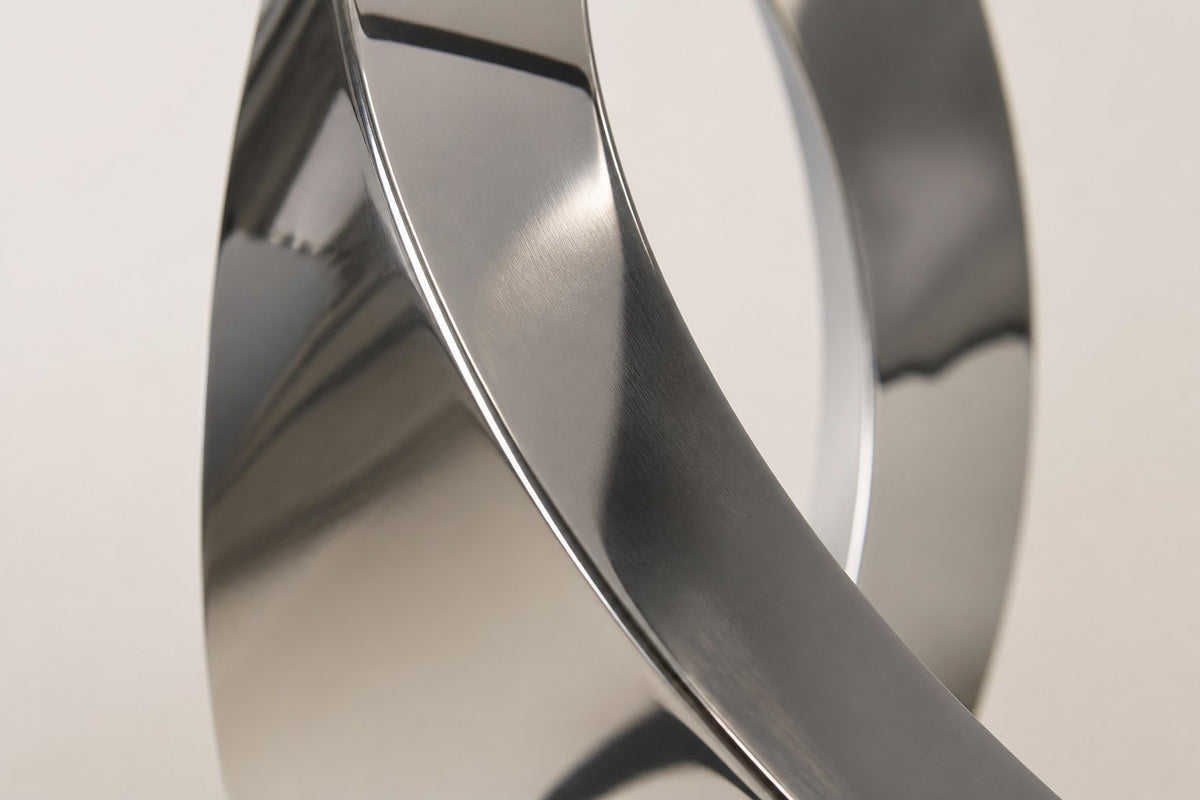 Barq — 200 cm mirror-polished steel twisting ribbon sculpture on a black base, close studio detail of the surface and material