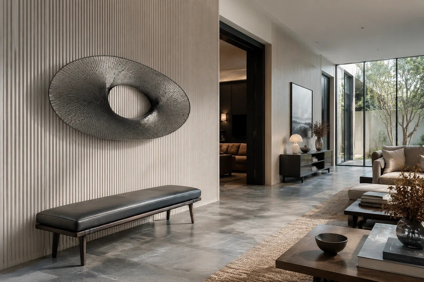 Broad woven-wire ellipse in pale grey with an open oval void, against a plaster wall.