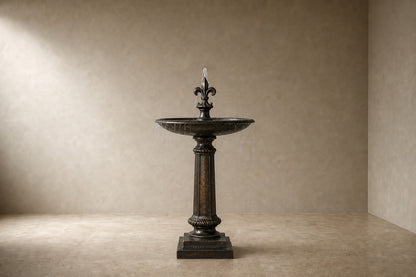Stone pedestal fountain Brimala Ø65, mottled dark bronze-brown, on a pale stone floor.