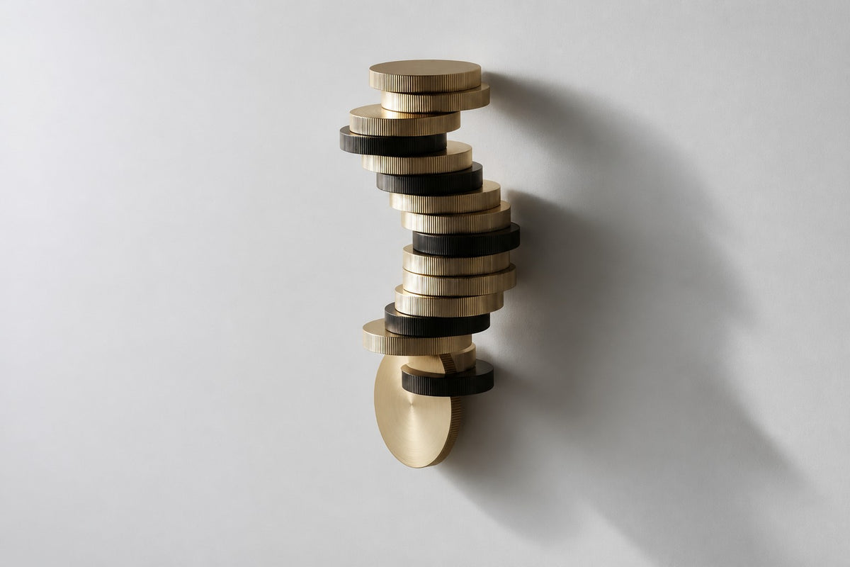 Cairn — 240 cm wall-mounted column of stacked ribbed brass and bronze discs, three-quarter studio view showing its profile
