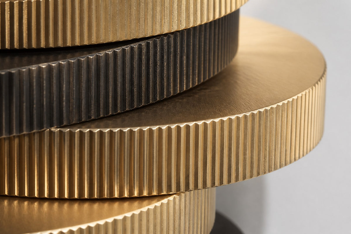 Cairn — 240 cm wall-mounted column of stacked ribbed brass and bronze discs, close studio detail of the surface and material