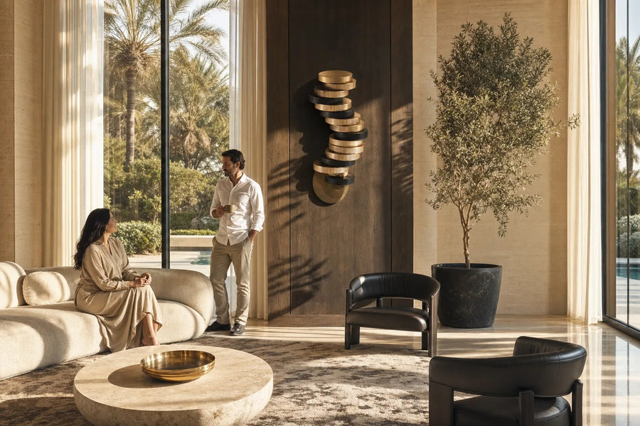 Cairn — 240 cm wall-mounted column of stacked ribbed brass and bronze discs, placed in a furnished room