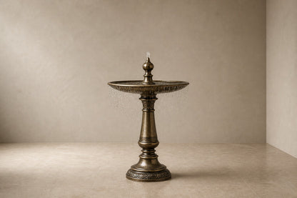 Stone pedestal fountain Cascina Ø65, antique bronze with olive depths, on a pale stone floor.