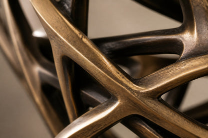 Bronze strut-cage figure sculpture Centina in a backbend on one leg, gilt and blackened, on a fluted travertine drum plinth.