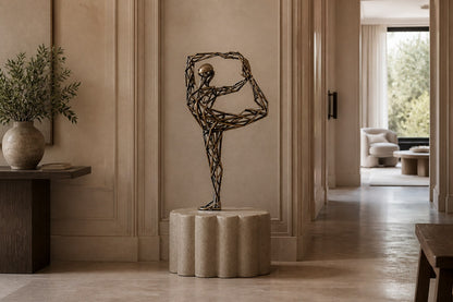Bronze strut-cage figure sculpture Centina in a backbend on one leg, gilt and blackened, on a fluted travertine drum plinth.