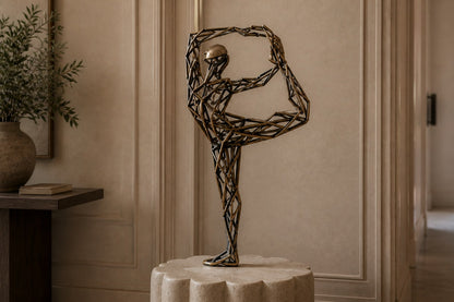 Bronze strut-cage figure sculpture Centina in a backbend on one leg, gilt and blackened, on a fluted travertine drum plinth.