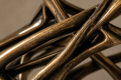 Bronze strut-cage figure sculpture Cesello in arabesque with arm extended, on a dark quilted stone block.