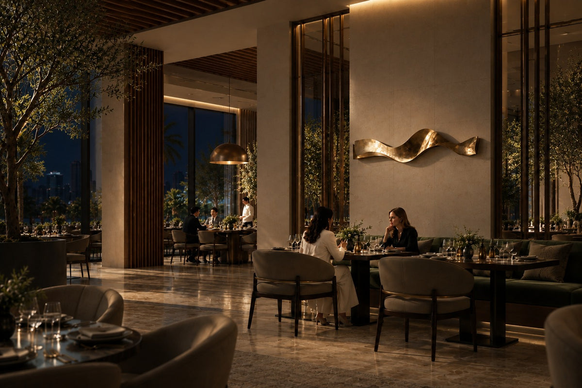Cinta — polished brass ribbon wall sculpture in three soft waves, the same room at night, lamps on