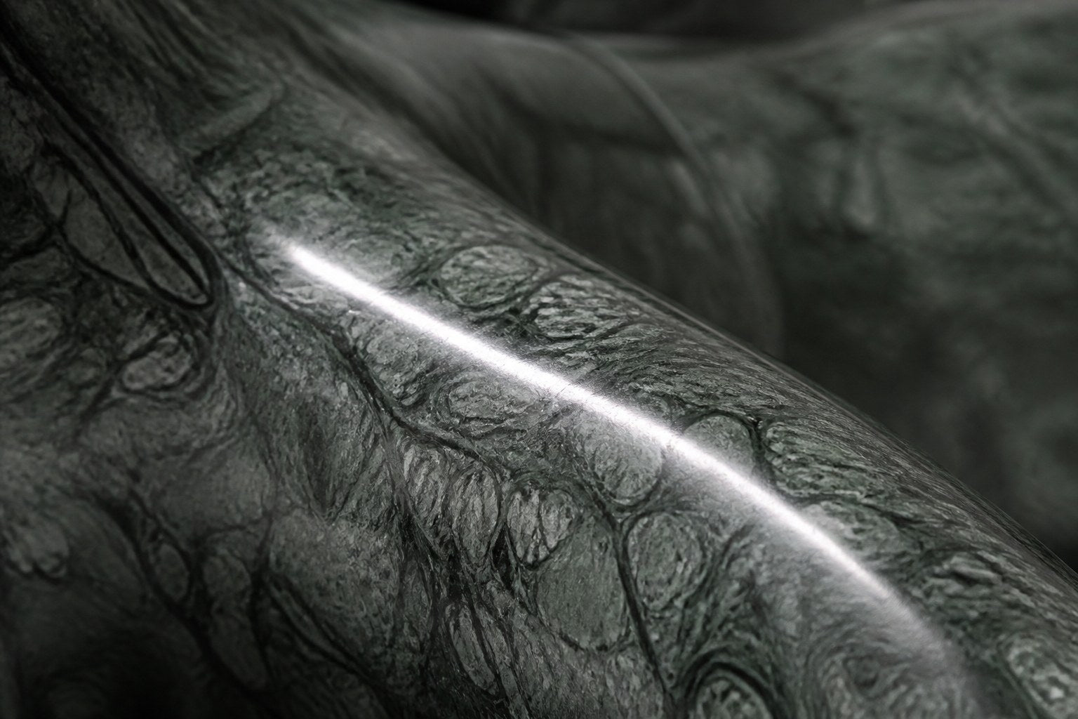 Deep green marble sculpture Collado, a reclining figure carved with its slab base from one block of veined green stone.