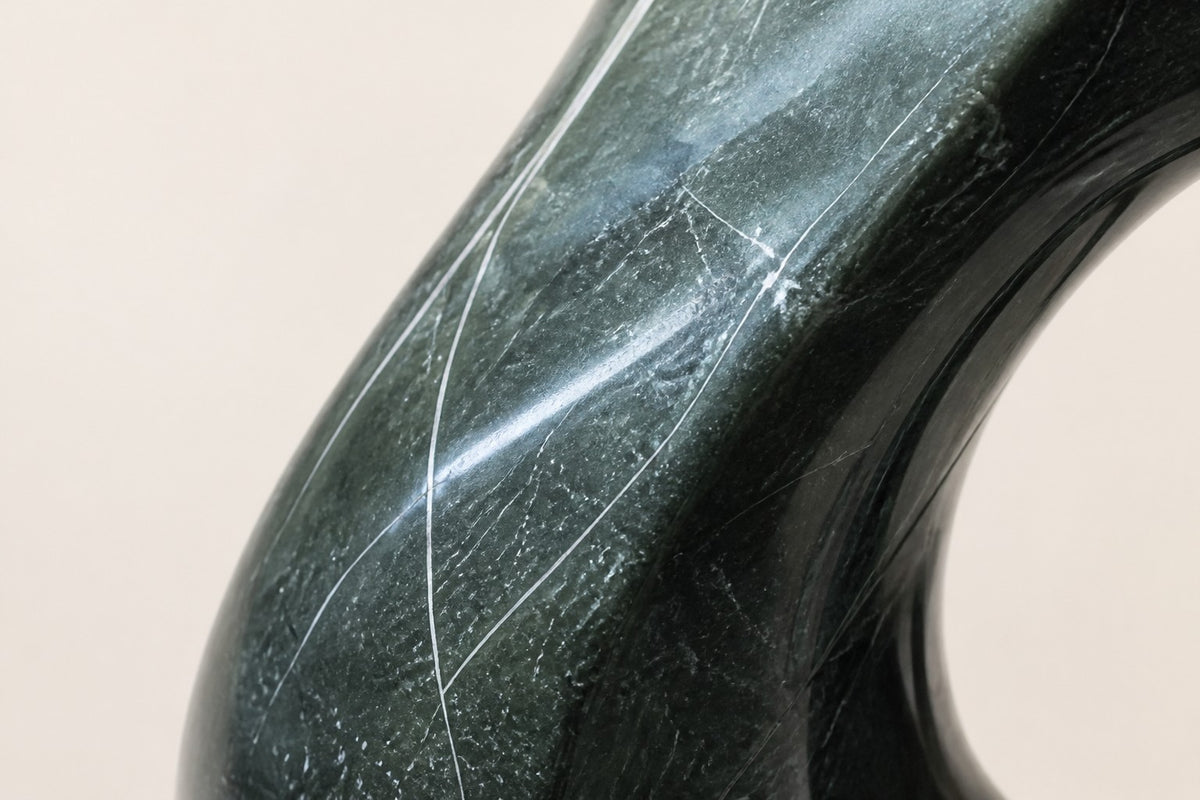VOID II — 180 cm green marble teardrop sculpture with a twist and an oval hole, close studio detail of the surface and material