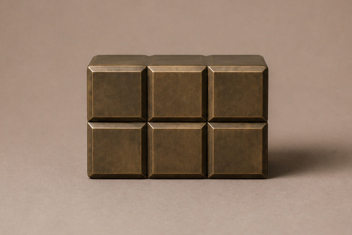Tall antique bronze column built as a grid of raised cushioned panels — viewed from directly above