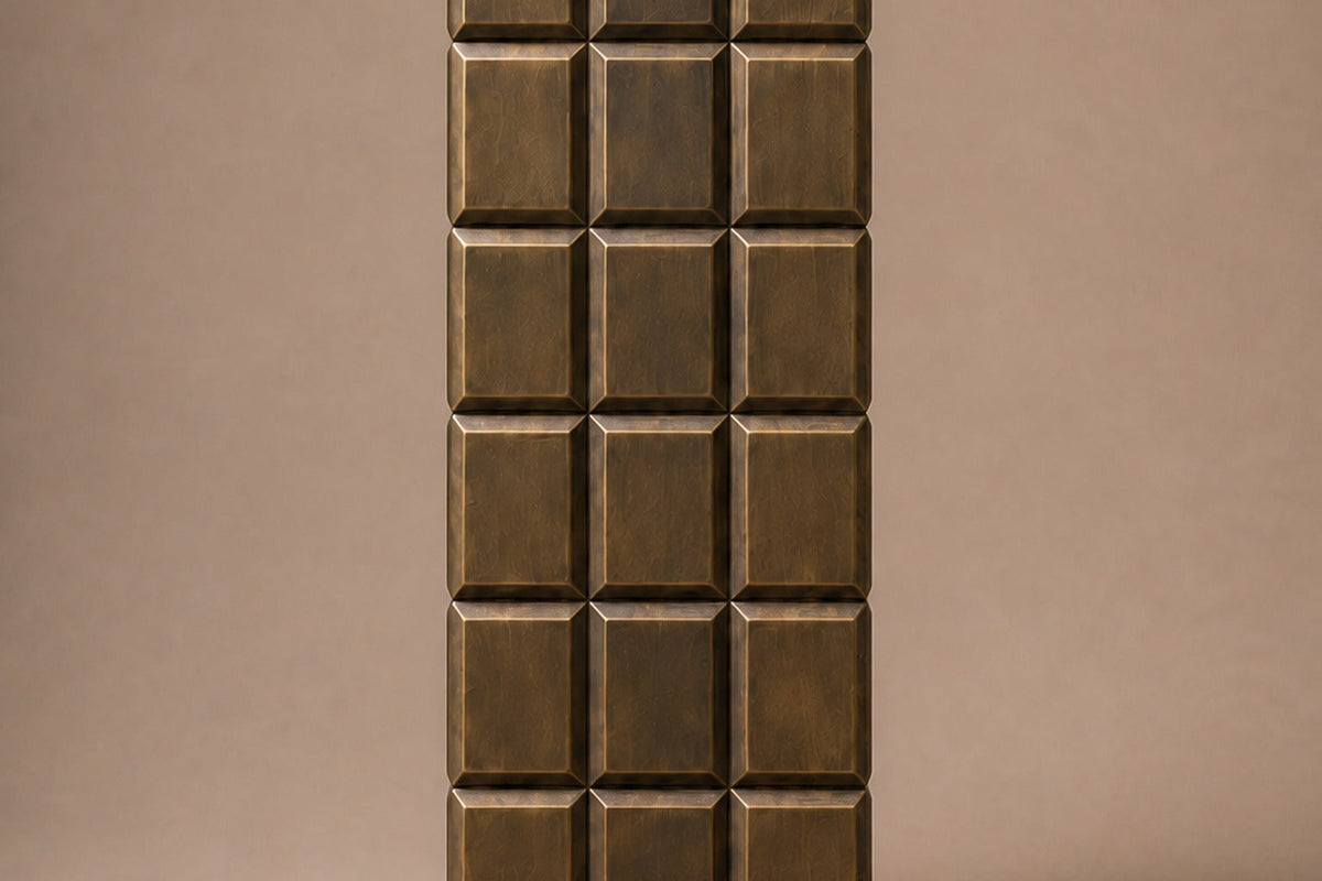 Tall antique bronze column built as a grid of raised cushioned panels — front elevation