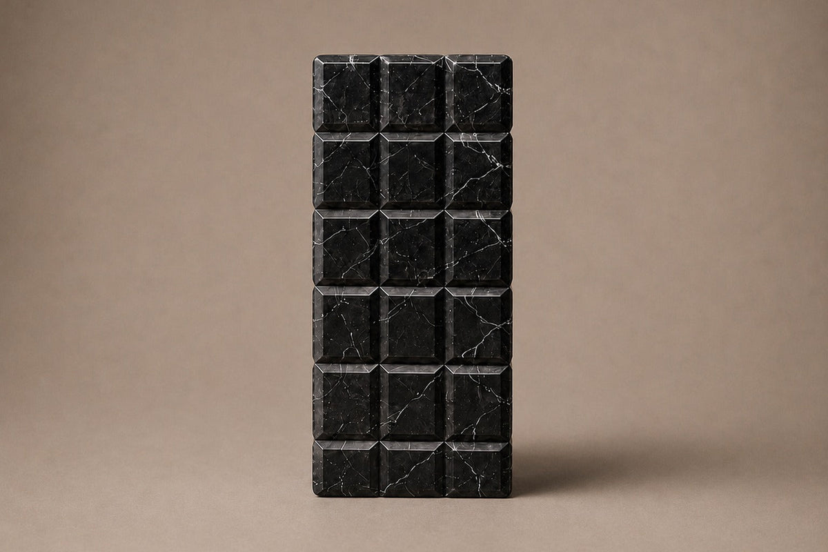 Tall black Nero Marquina marble column carved into a grid of raised cushioned panels — front elevation