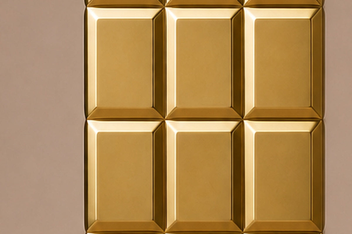 Tall polished brass column built as a grid of raised cushioned panels — close detail of the surface