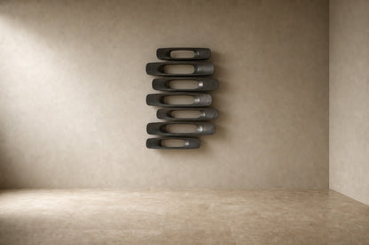 Gunmetal with bright edges bronze wall sculpture Scalino, graduated blades stepped across a concealed spine, on a plaster wall.