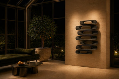Gunmetal with bright edges bronze wall sculpture Scalino, graduated blades stepped across a concealed spine, on a plaster wall.