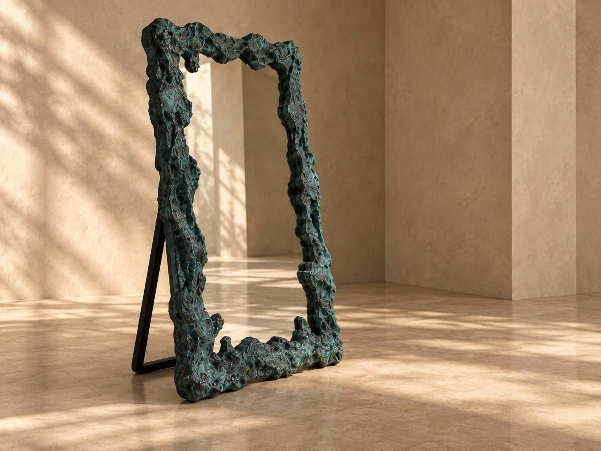 Estanque — 110 × 200 cm tall standing mirror with a rough cast frame in blue-green patinated bronze, three-quarter studio view showing its profile