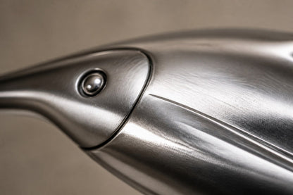 Mirror-polished stainless steel ring sculpture Estero Ø70, eight linked forms nose to tail, on a black granite block.