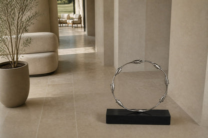 Mirror-polished stainless steel ring sculpture Estero Ø70, eight linked forms nose to tail, on a black granite block.