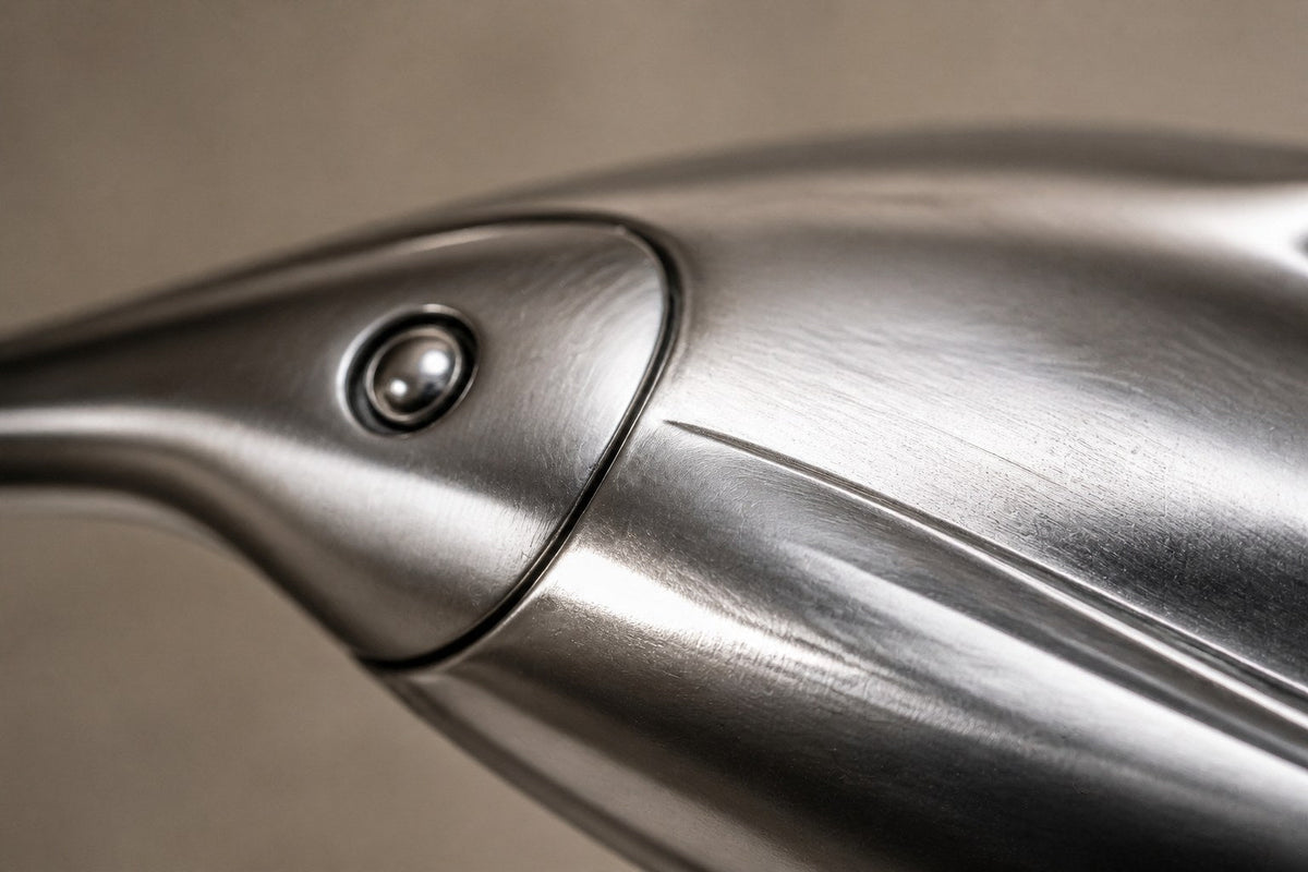 Mirror-polished stainless steel ring sculpture Estero Ø70, eight linked forms nose to tail, on a black granite block.