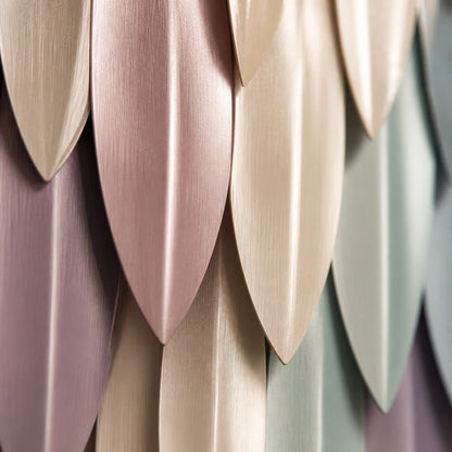Pale rose through to celadon steel wall sculpture Alba, fine pointed scales layered on a leaf armature, on a plaster wall.