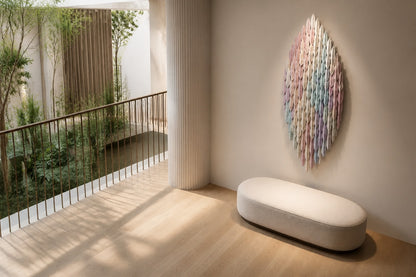Pale rose through to celadon steel wall sculpture Alba, fine pointed scales layered on a leaf armature, on a plaster wall.
