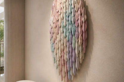 Pale rose through to celadon steel wall sculpture Alba, fine pointed scales layered on a leaf armature, on a plaster wall.