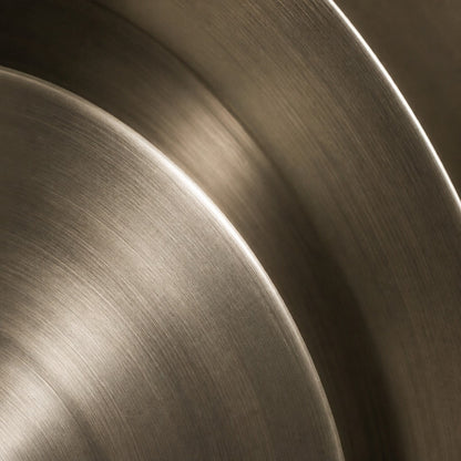 Bright silver stainless steel wall sculpture Plata, nested spun dishes stepping to a turned centre, on a plaster wall.