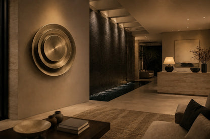 Bright silver stainless steel wall sculpture Plata, nested spun dishes stepping to a turned centre, on a plaster wall.