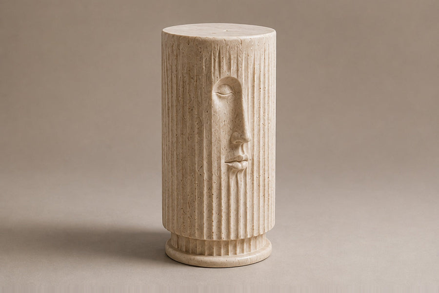 Fluted cream travertine drum on a round moulded foot, with a face carved through the flutes — three-quarter studio view of the whole pedestal
