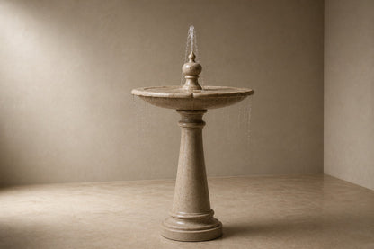 Pale limestone pedestal fountain Fontena Ø65, cream with open fossil speckle, on a pale stone floor.