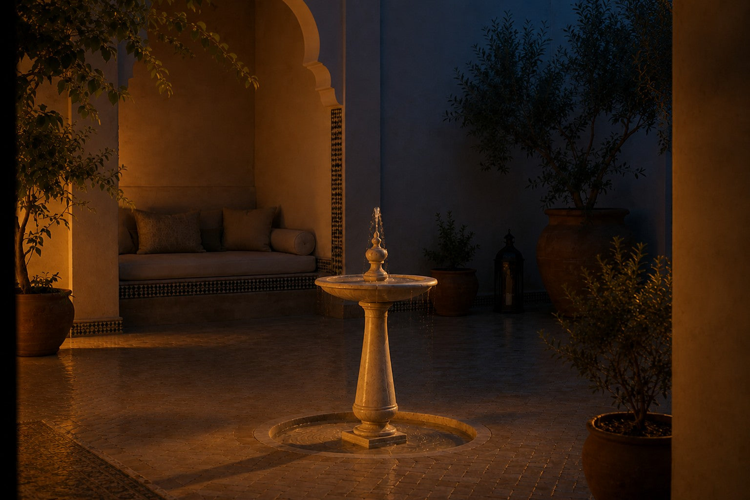 Pale limestone pedestal fountain Fontena Ø65, cream with open fossil speckle, on a pale stone floor.