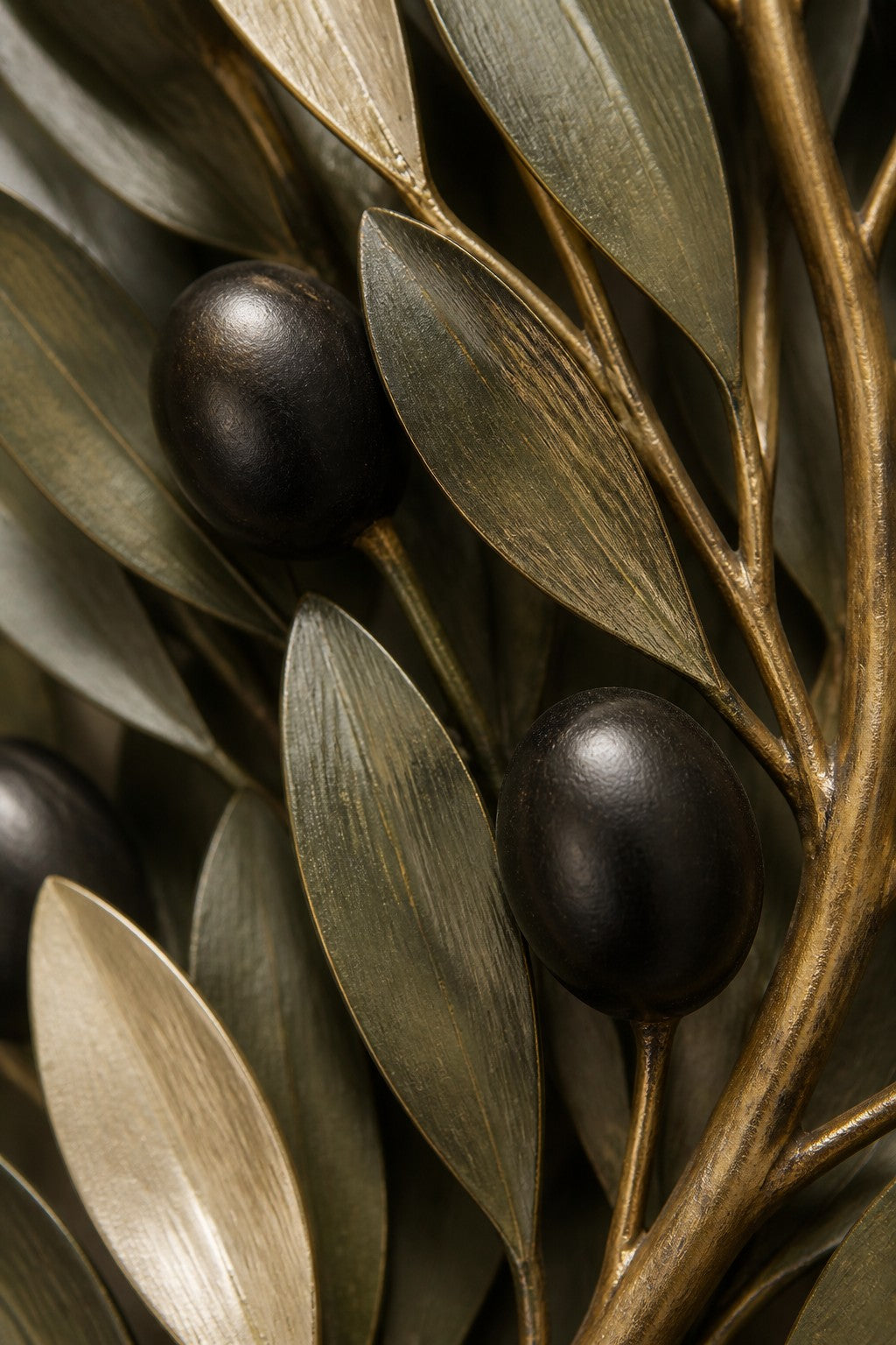 Olive green and dark bronze bronze wall sculpture Ramoscello, cast branch with individually mounted leaves and fruit, on a plaster wall.