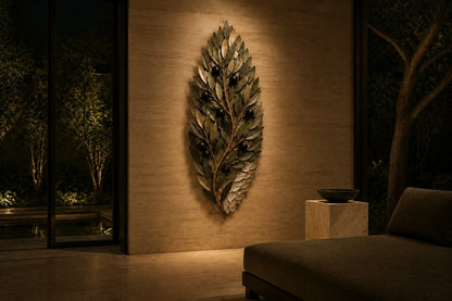 Olive green and dark bronze bronze wall sculpture Ramoscello, cast branch with individually mounted leaves and fruit, on a plaster wall.