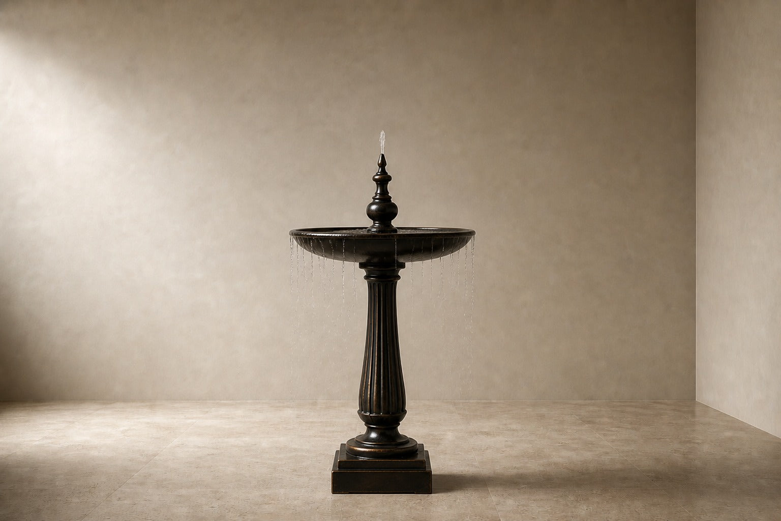 Stone pedestal fountain Goccia Ø65, near-black with a soft sheen, on a pale stone floor.