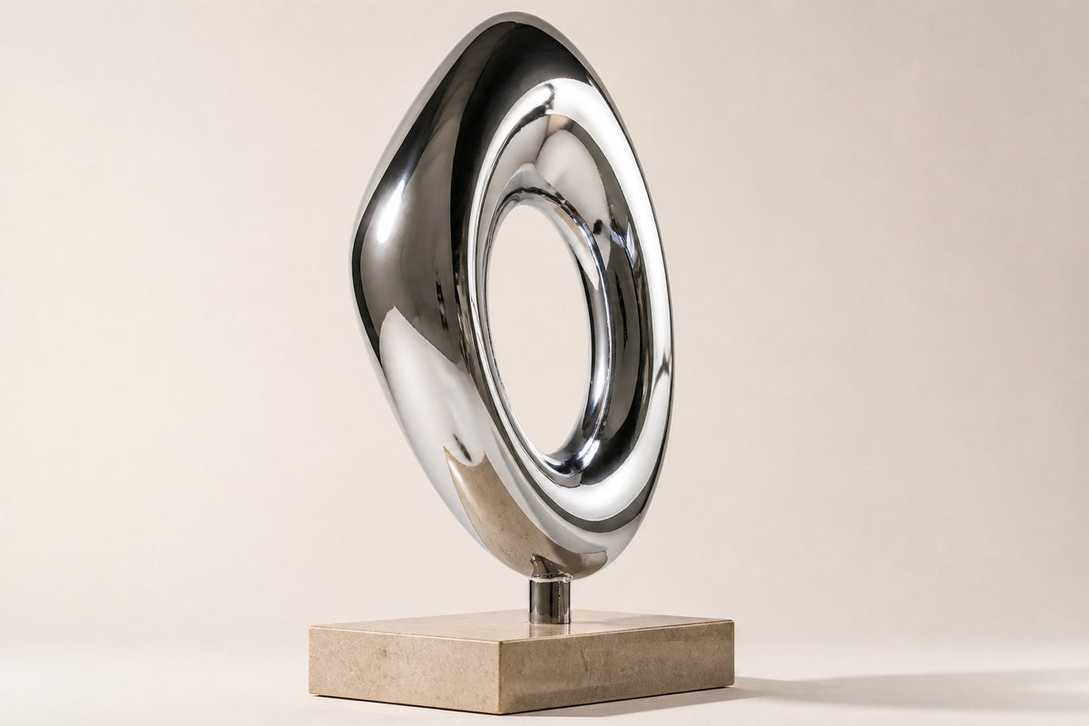 Halqa — mirror chrome ring sculpture on a beige marble base, studio side angle showing its depth