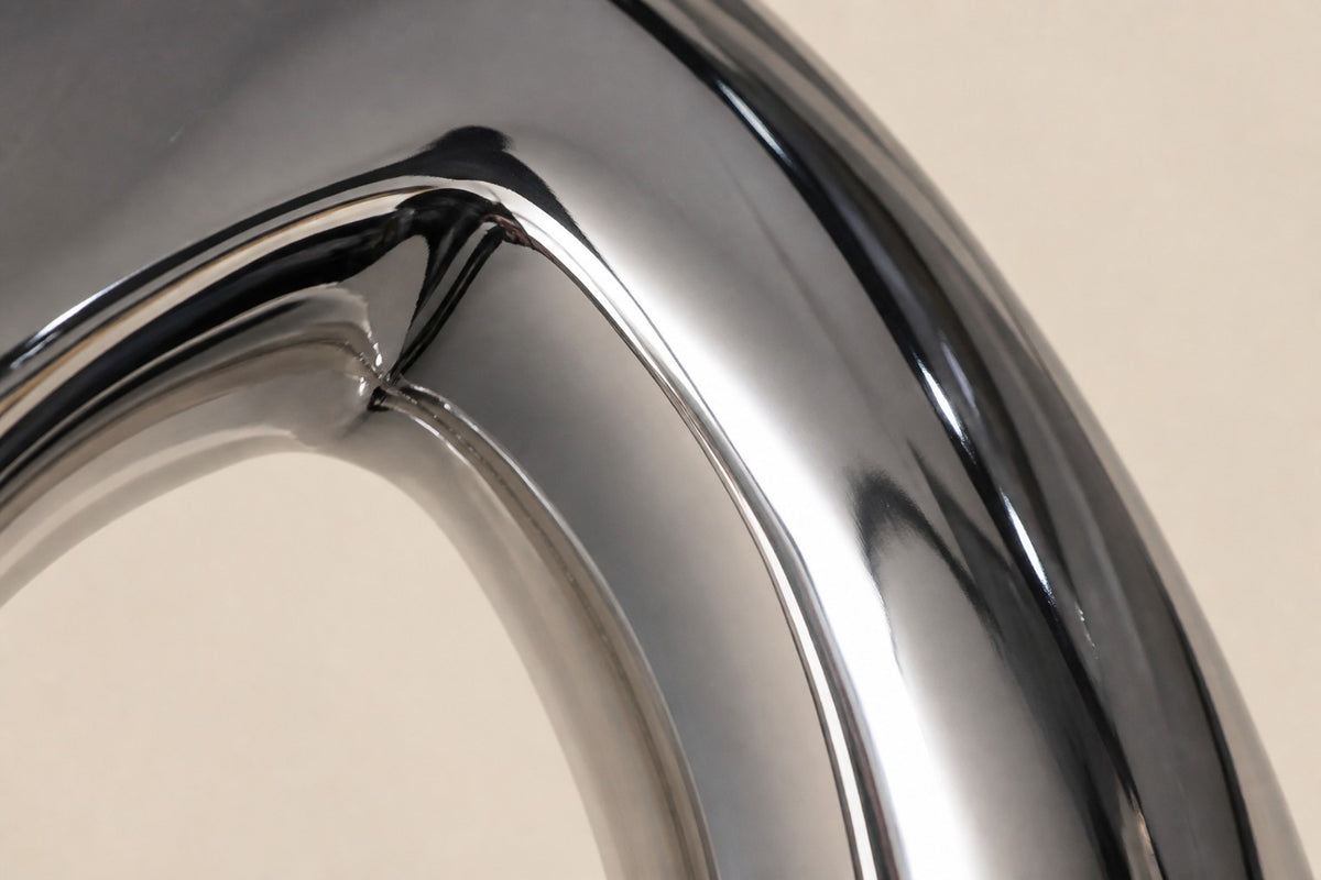 Halqa — mirror chrome ring sculpture on a beige marble base, close detail of the surface and edge